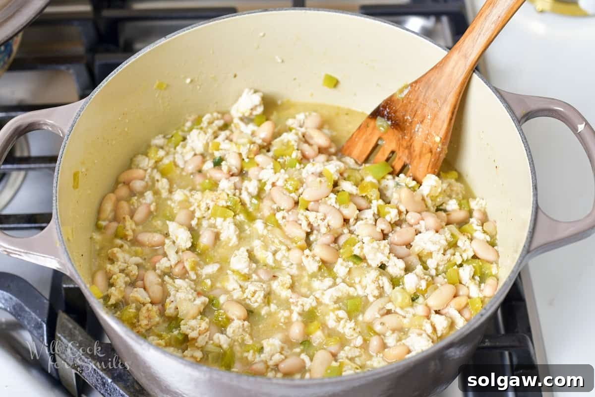 Chicken stock being poured into the chili pot.