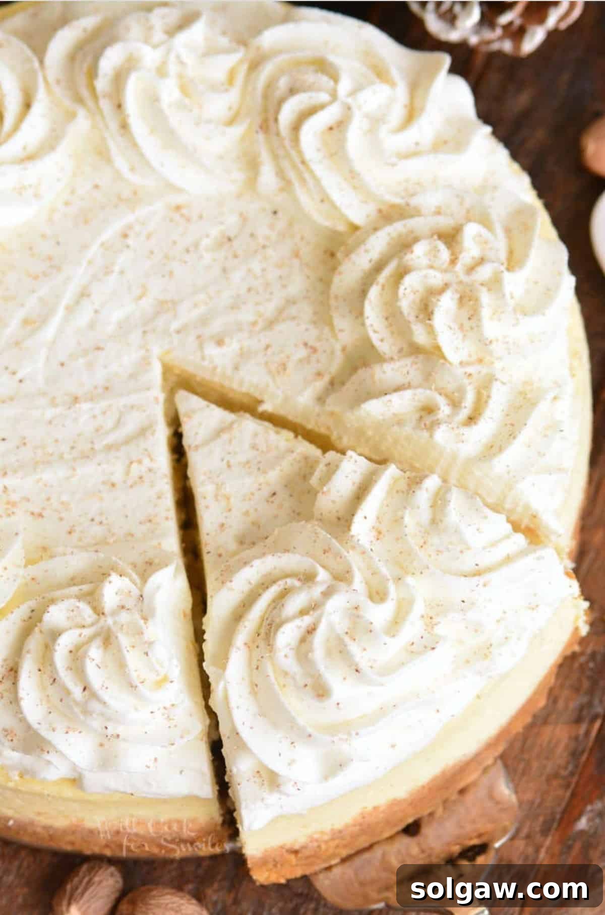 Yuletide Eggnog Cheesecake 8 A whole Eggnog Cheesecake with a slice removed, displaying its moist interior and perfect crust, set on a festive holiday table.