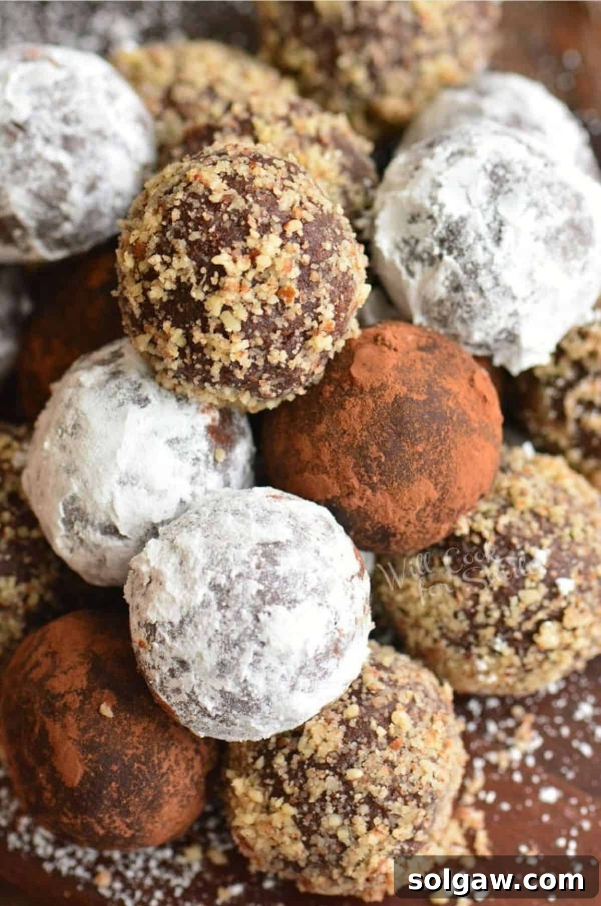 Heavenly Homemade Rum Balls 2 Stacked rum balls coated in nuts, cocoa powder, and powdered sugar, invitingly arranged.
