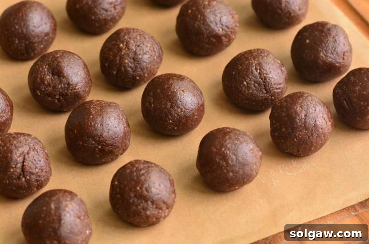 Heavenly Homemade Rum Balls 5 Several rolled rum balls neatly arranged on parchment paper, awaiting their coating.