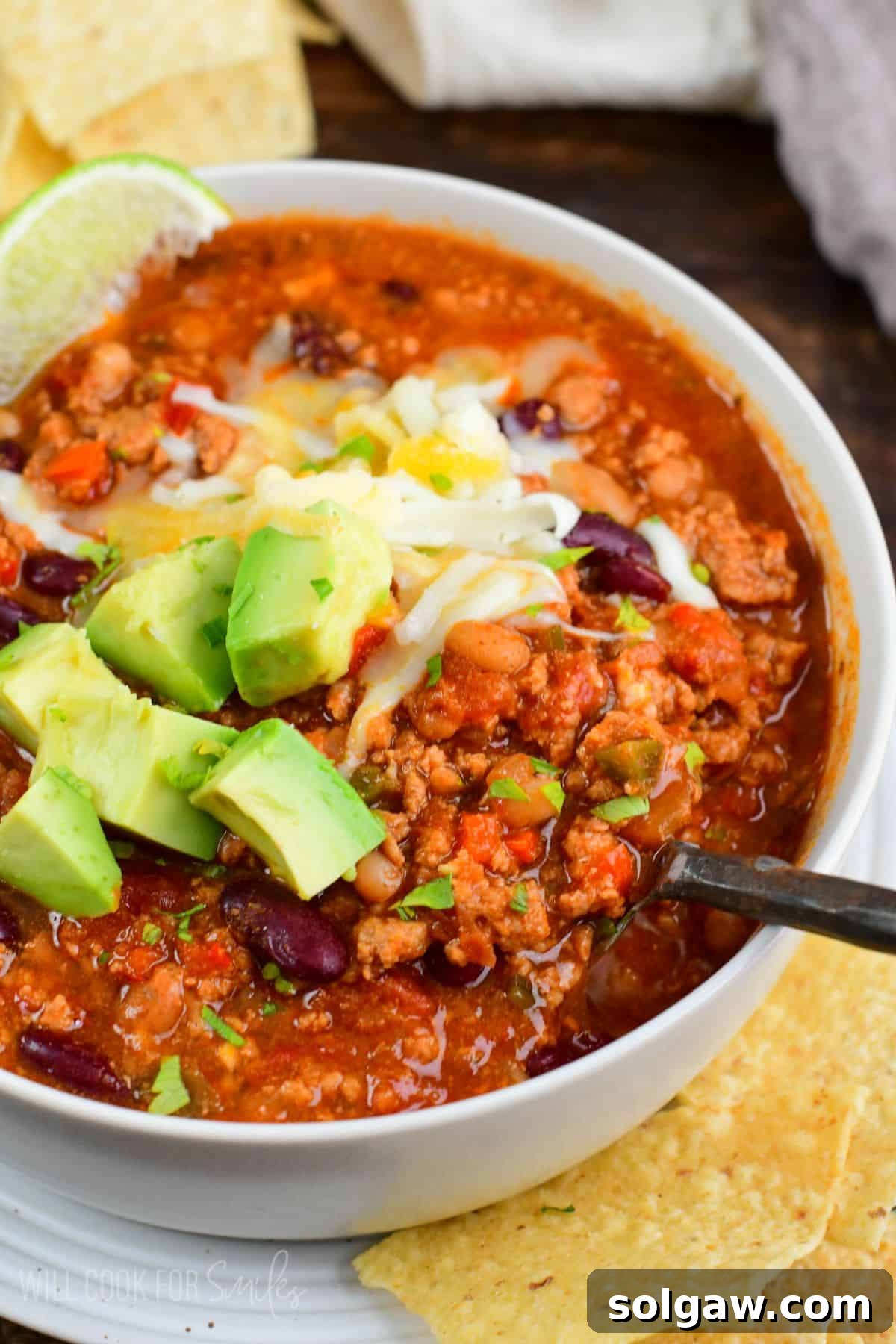 A metal spoon scooping a generous portion of turkey chili from a bowl, highlighting its rich texture.