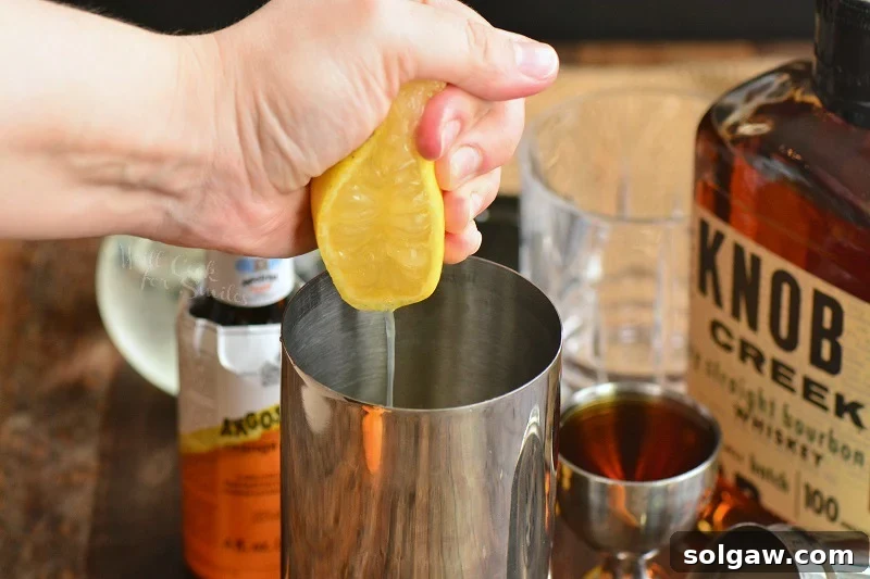 Whiskey Sour Two Takes 3 Squeezing fresh lemon juice into a cocktail shaker, illustrating the importance of fresh ingredients for a Whiskey Sour.