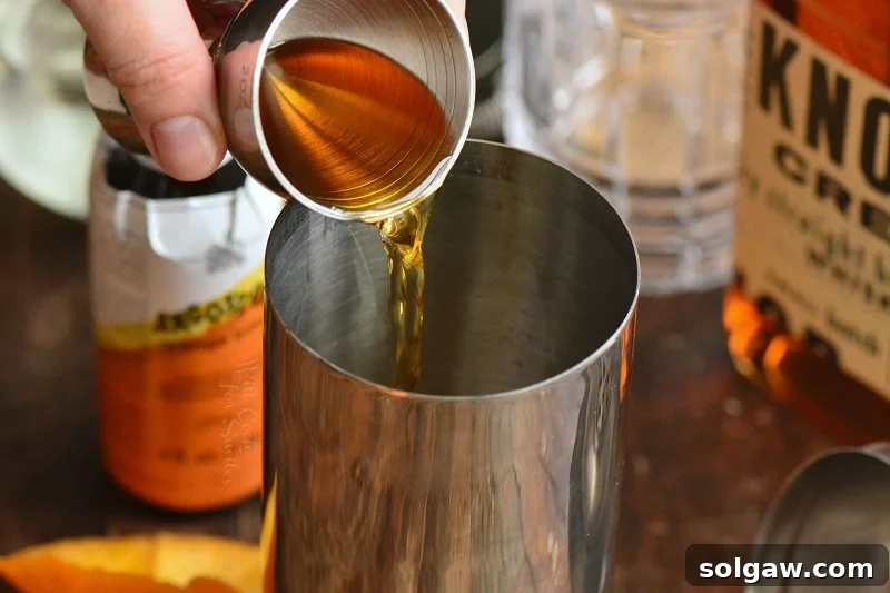 Whiskey Sour Two Takes 4 Pouring bourbon whiskey into a cocktail shaker, a crucial step in making a Whiskey Sour.