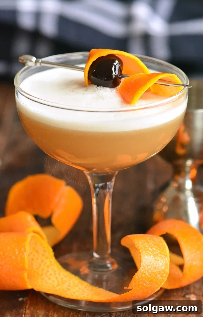 Whiskey Sour Two Takes 9 A beautiful vertical photo of a Whiskey Sour cocktail in a glass, garnished with an orange slice.