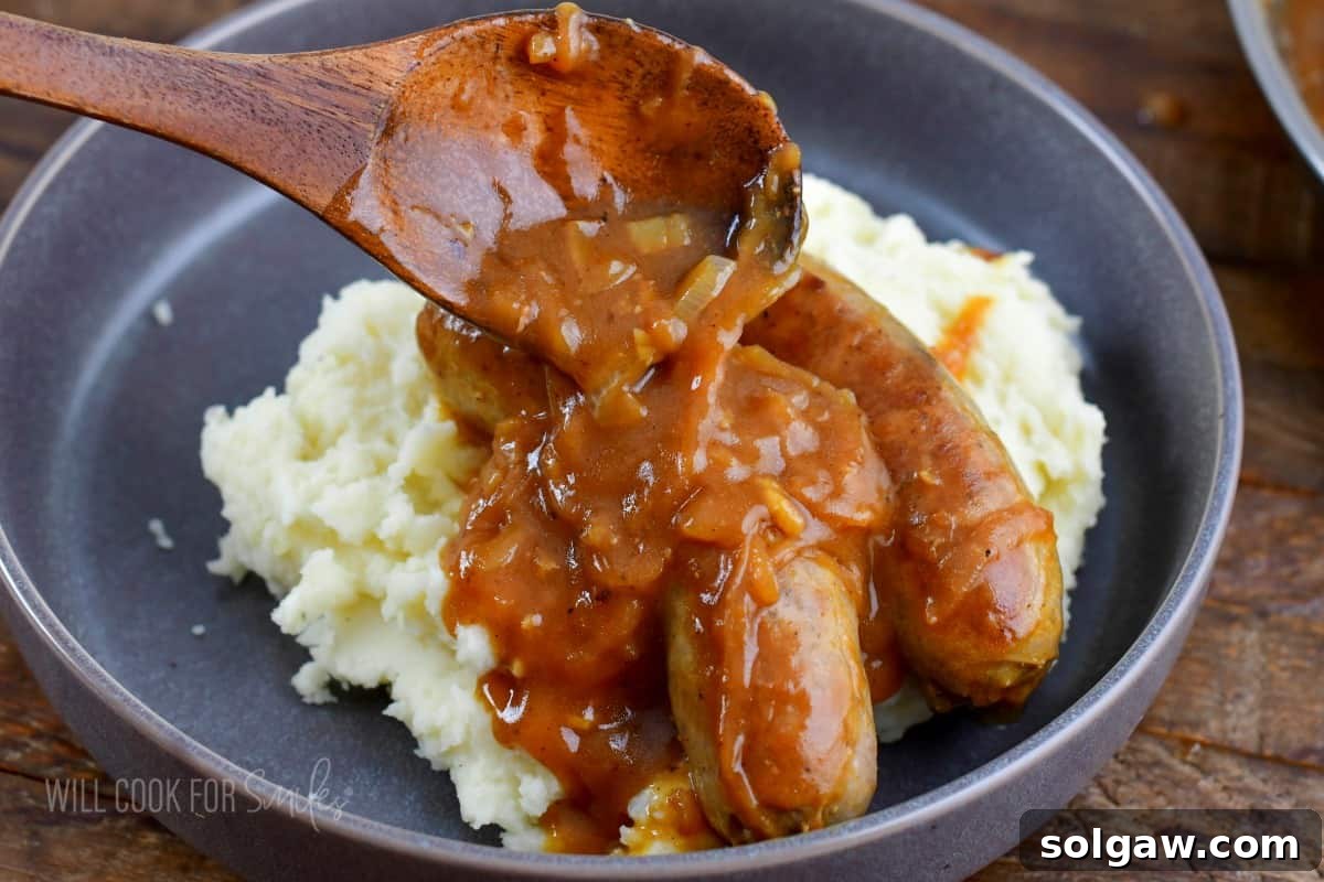 Onion Gravy Smothered Sausages and Mash 5 adding gravy on top of the sausages and mashed potatoes.