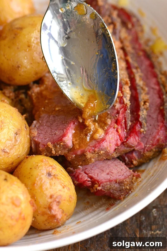 One-Pan Corned Beef with Crispy Potatoes 7 A close-up of sliced corned beef brisket with baby gold potatoes, glistening with savory juices, demonstrating the tenderness and moisture of the dish.