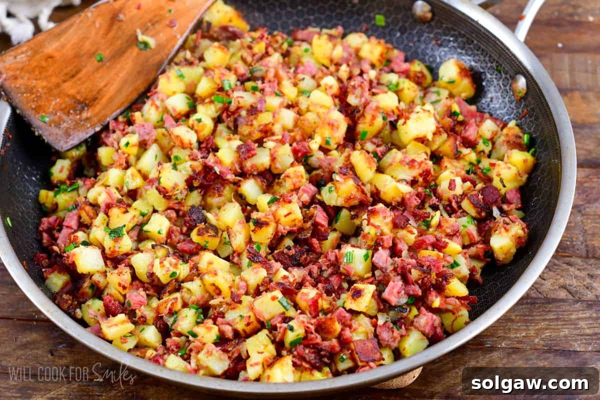 corned beef hash in a pan with a wooden spoon.