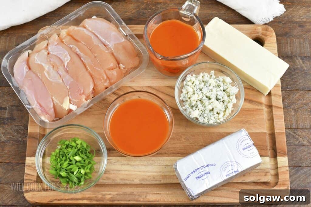 Ingredients for homemade Buffalo Chicken Dip laid out on a wooden cutting board.