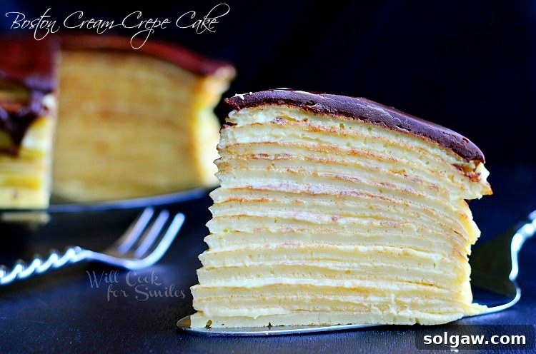 Boston Cream Mille Crepe 4 A close-up view of a single slice of Boston Cream Crepe Cake, perfectly cut to reveal its many delicate layers, placed on a cake server. The remainder of the cake is visible in the background.