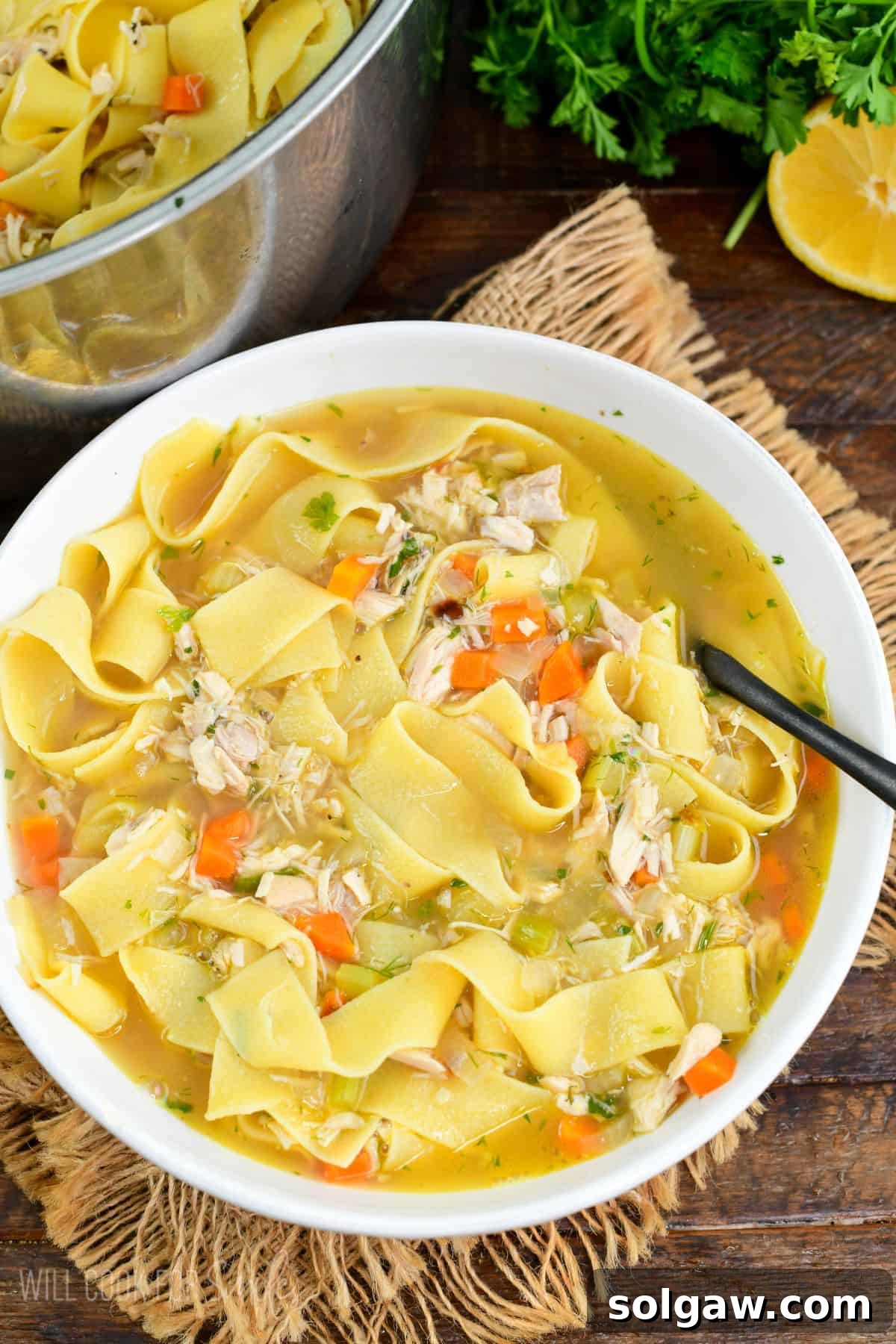 Hearty homemade chicken noodle soup served in a white bowl, filled with noodles, vegetables, and warm flavorful broth.