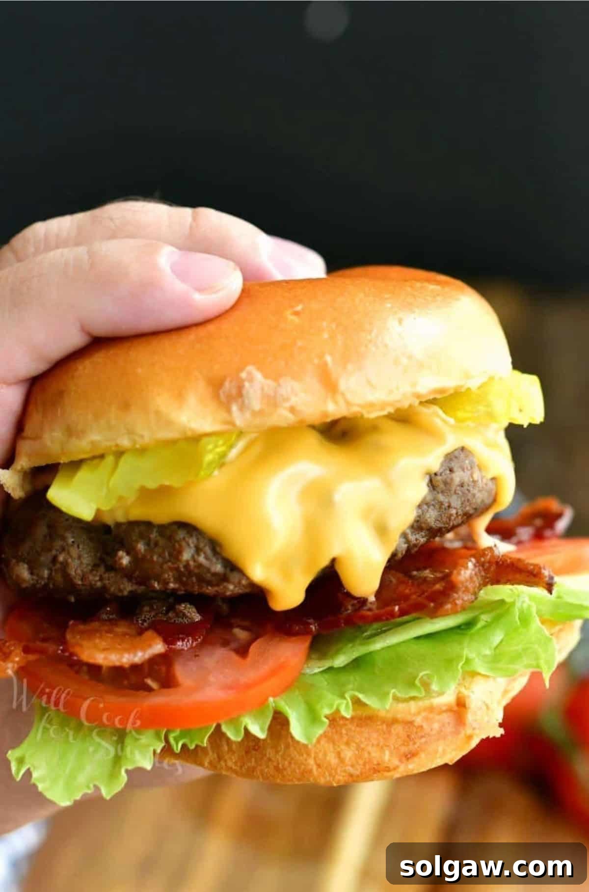 Crafting the Ultimate Burger 2 Hand holding a perfectly cooked cheeseburger with fresh toppings, ready to eat.