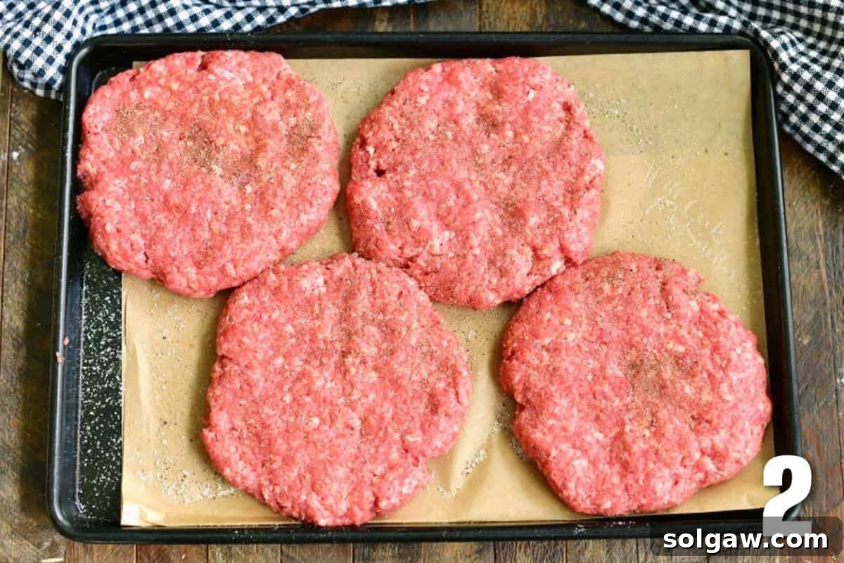 Crafting the Ultimate Burger 4 Four perfectly shaped raw burger patties resting on parchment paper in a metal tray.