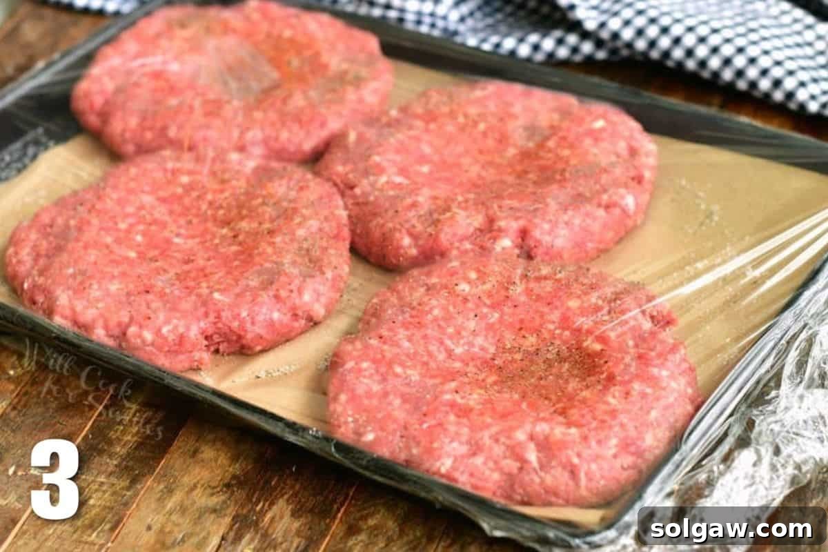 Crafting the Ultimate Burger 5 Four raw burger patties with a thumbprint dent in the center, covered with plastic wrap.