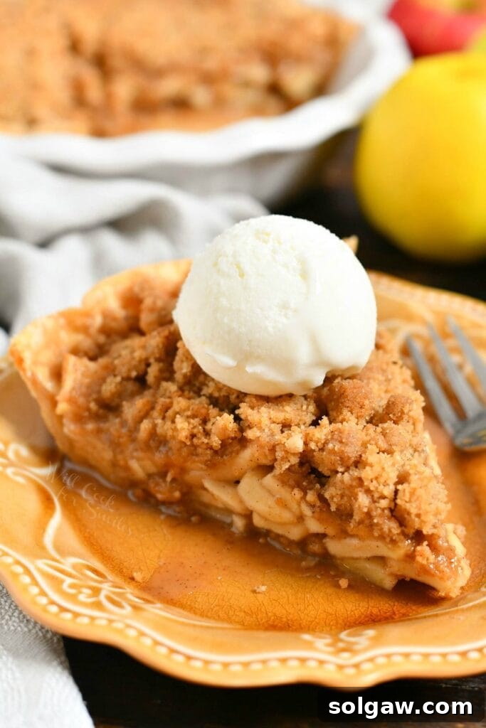Plated slice of homemade apple dessert with crumble topping and vanilla ice cream on top