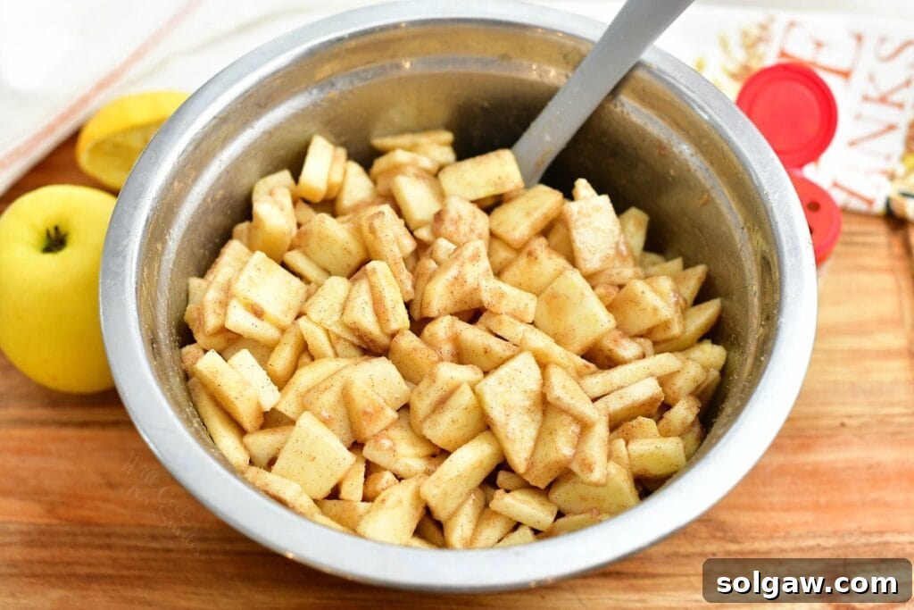 Stirring fresh apple slices in a bowl with cinnamon sugar mixture