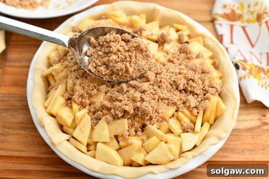 Using spoon to add streusel topping for apple pie