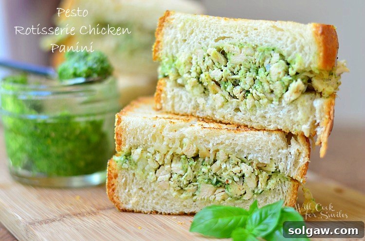 Close-up of a Pesto Rotisserie Chicken Panini cut in half, showing the melted Fontina cheese and chicken filling
