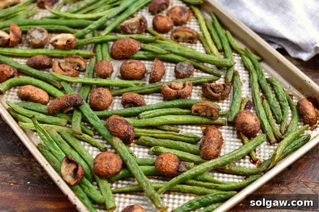Savory Mushroom and Green Bean Roast 5 Roasted green beans and mushrooms spread out in a single layer on a rimmed baking sheet.