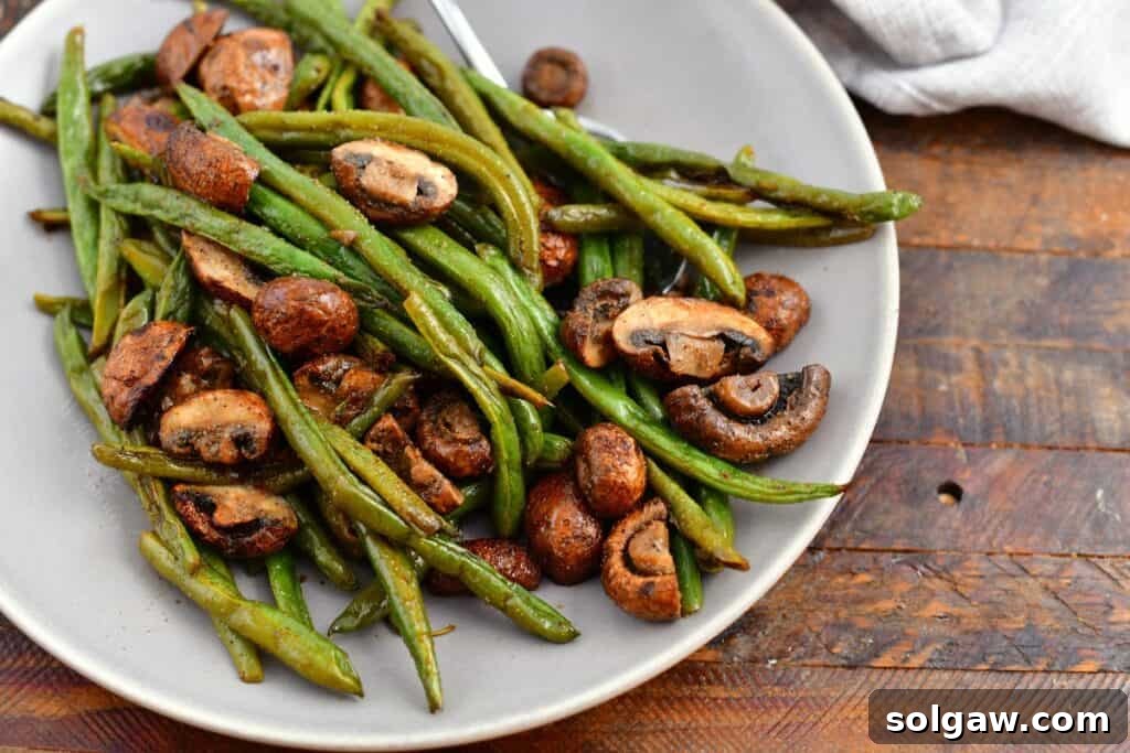 Savory Mushroom and Green Bean Roast 6 Overhead view of a fresh vegetable side dish, with vibrant green beans and earthy mushrooms in a white bowl.