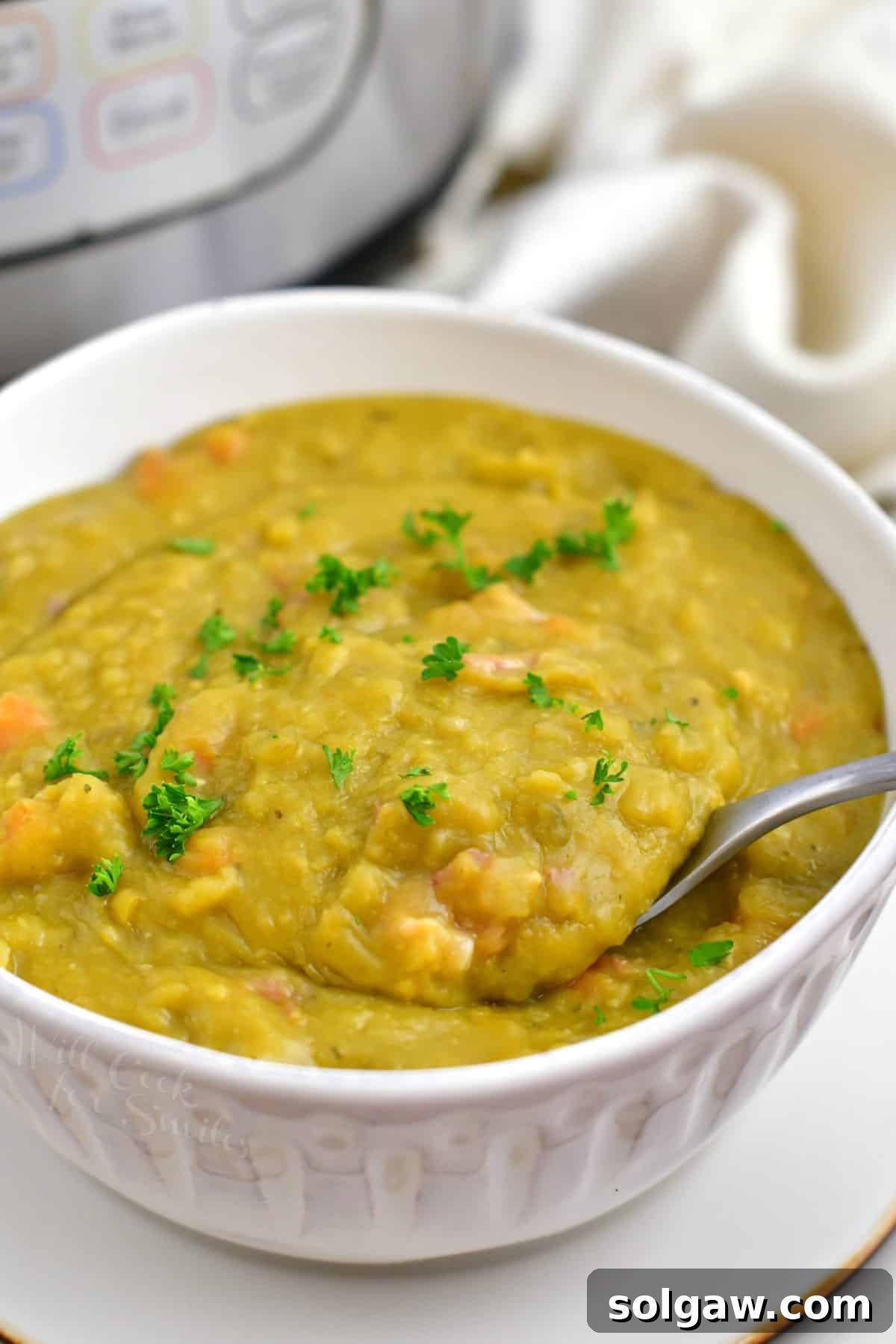 closeup image: thick green split pea soup in white bowl