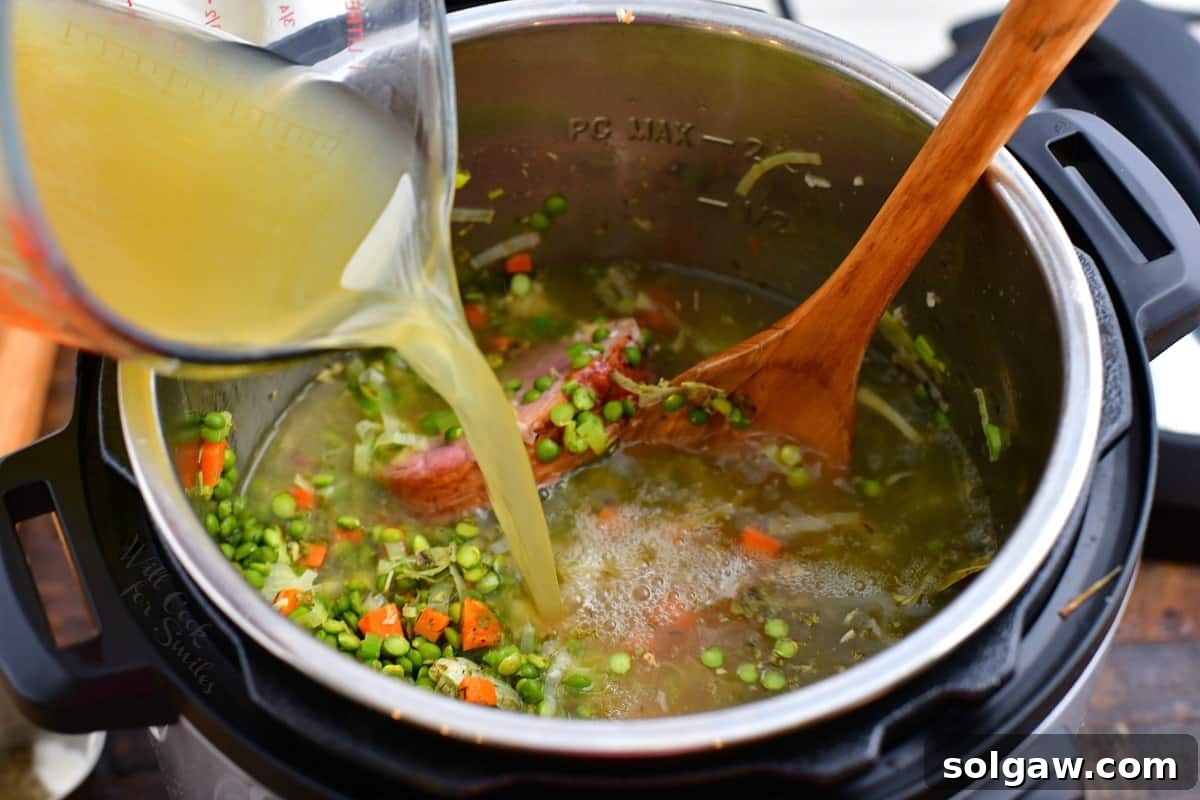 pouring chicken stock into a pressure cooker to make green pea soup recipe.