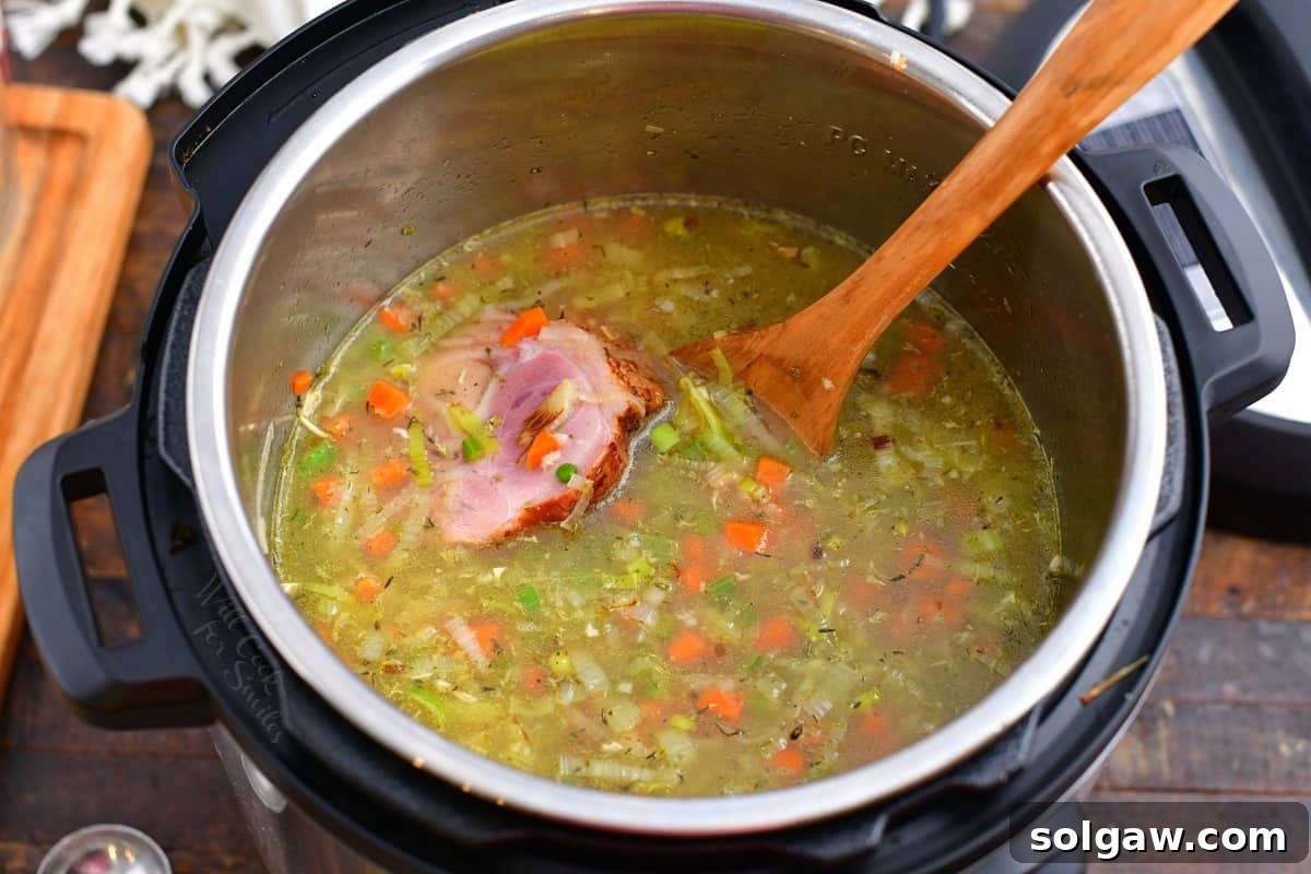 ham and vegetable soup in pressure cooker with wooden spoon.