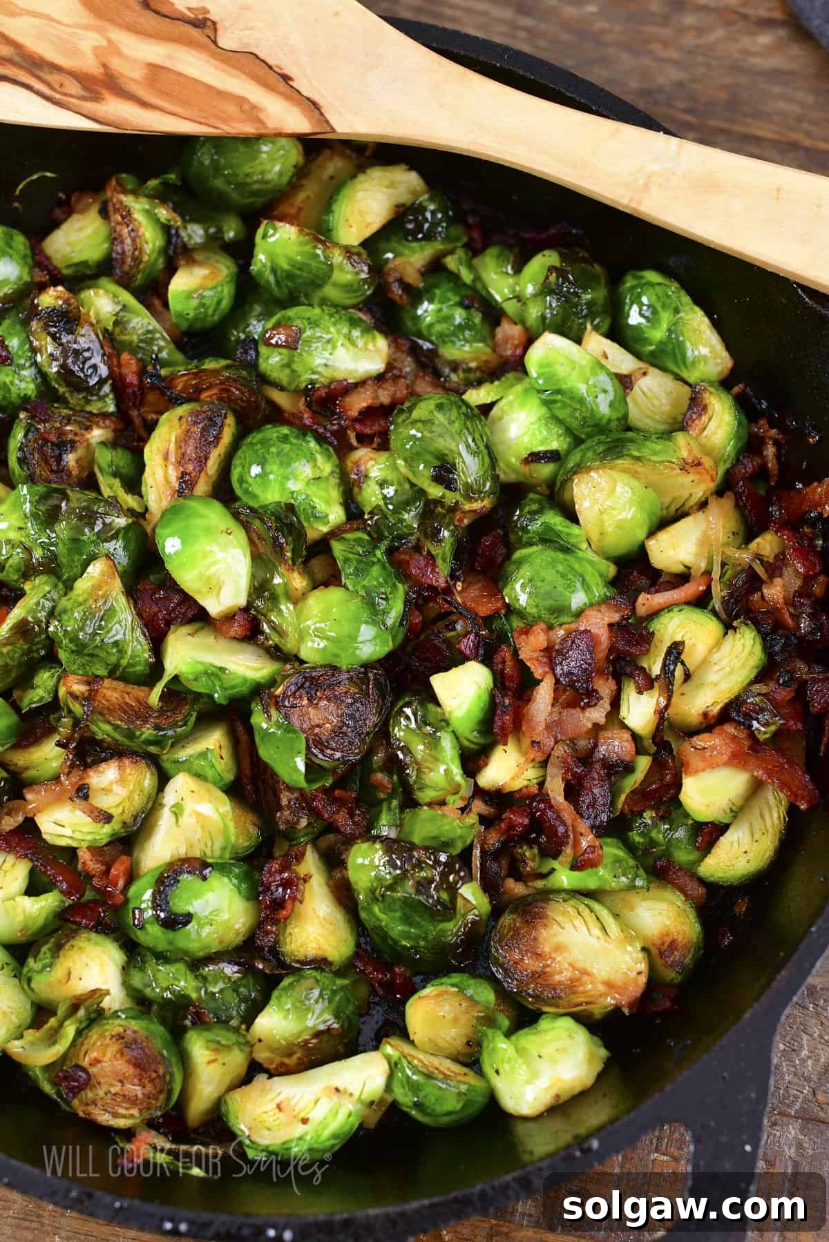 Closeup of crispy pan roasted Brussels sprouts with bacon and shallots in a skillet.