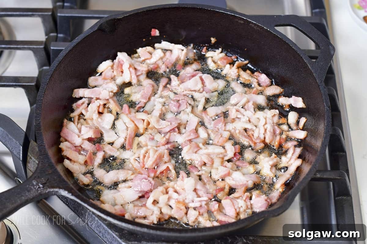 Cooking diced bacon pieces in a hot skillet until crispy.