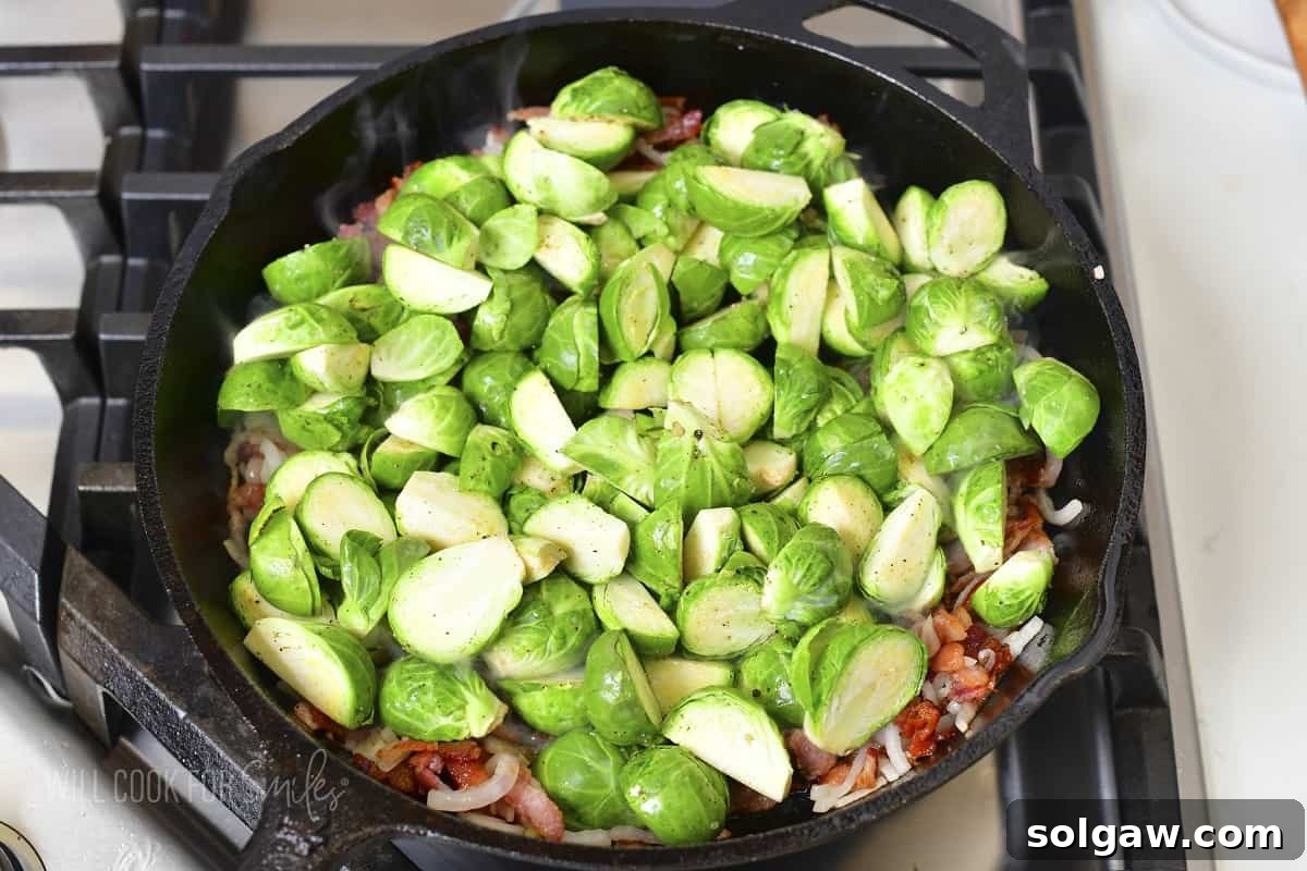 Adding prepared Brussels sprouts to the hot skillet with onions and bacon.