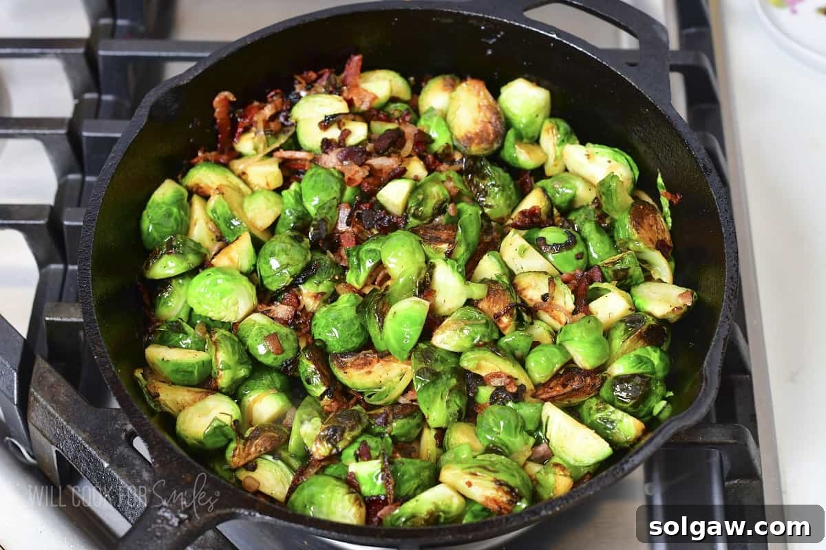 Cooked Brussels sprouts, bacon, and shallots beautifully caramelized in a skillet.