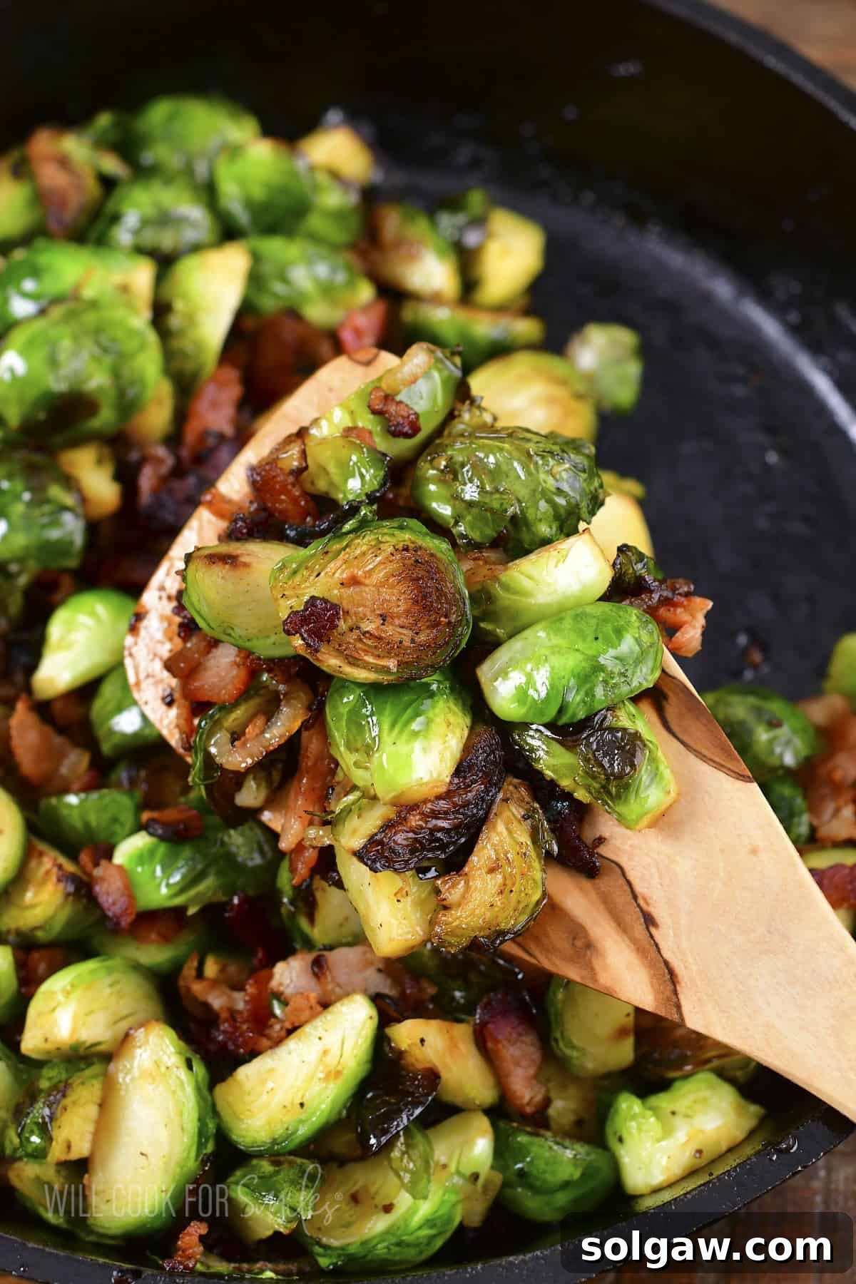 Scooping out a generous portion of roasted Brussels sprouts from the pan, ready to serve.