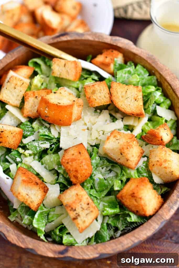Overhead image of a rustic wooden bowl filled with green salad and homemade croutons, ready to serve