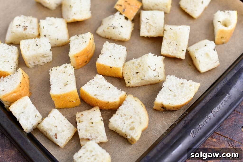 Freshly cut bread cubes spread on a baking sheet, ready for seasoning and toasting into homemade croutons