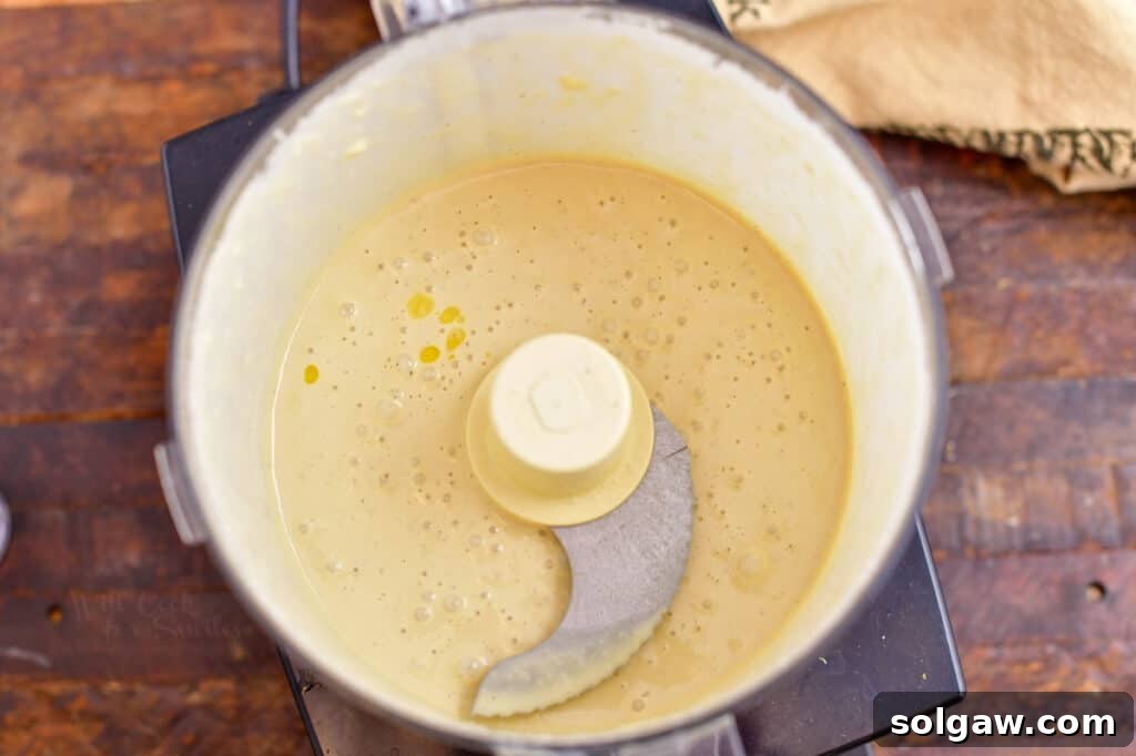 Smooth and creamy homemade Caesar salad dressing in the bowl of a food processor, ready to use