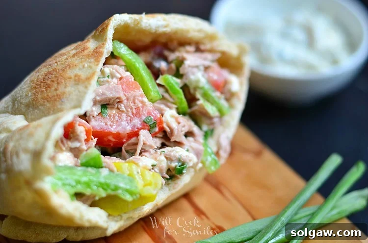 Coastal Tuna Pita with Bright Herb Aioli 3 Fresh Greek Tuna Pita ingredients artfully arranged on a cutting board, including tuna, vibrant tomatoes, and crisp green peppers