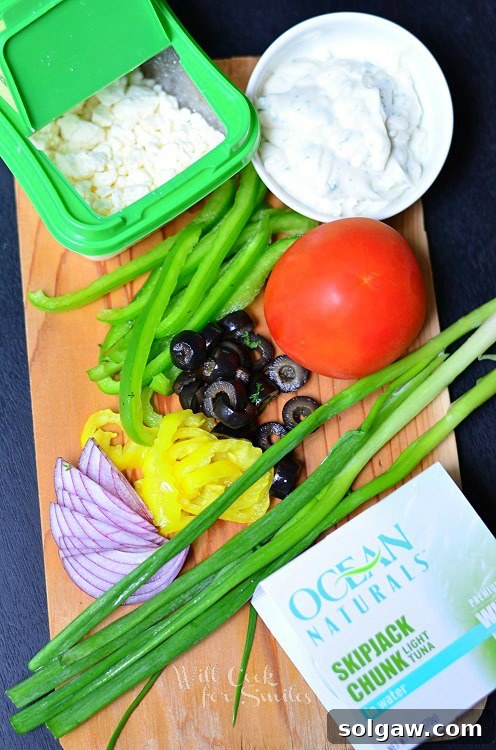 Coastal Tuna Pita with Bright Herb Aioli 4 A vibrant selection of ingredients for Greek Tuna Pita laid out on a cutting board, including fresh vegetables, tuna, and herbs