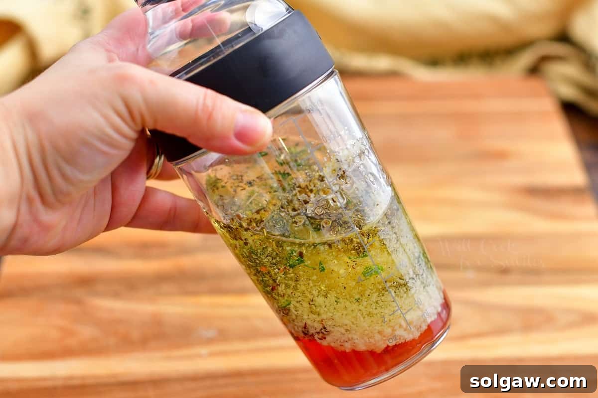 Zesty Italian Vinaigrette 6 ingredients for vinaigrette recipe being shaken together in a glass shaker.