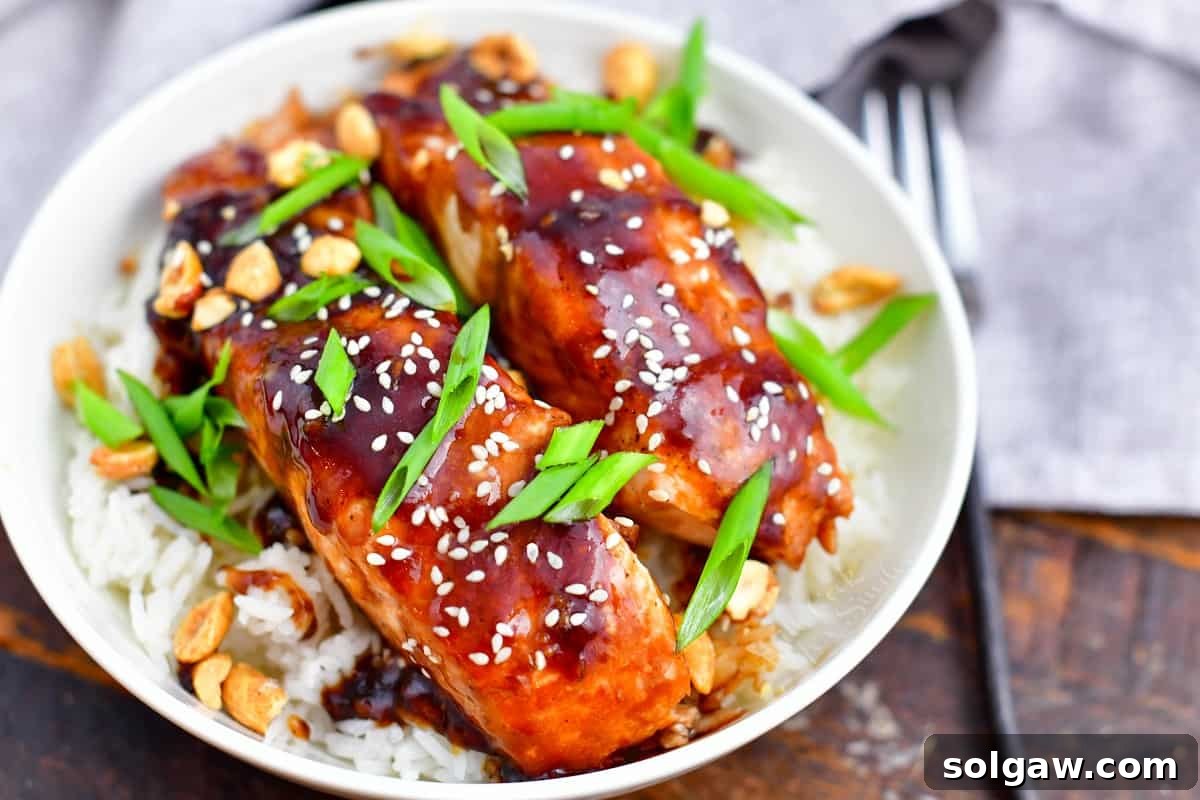 Sticky Sweet Teriyaki Salmon 7 closeup: teriyaki salmon topped with scallions and sesame seeds on a bed of rice