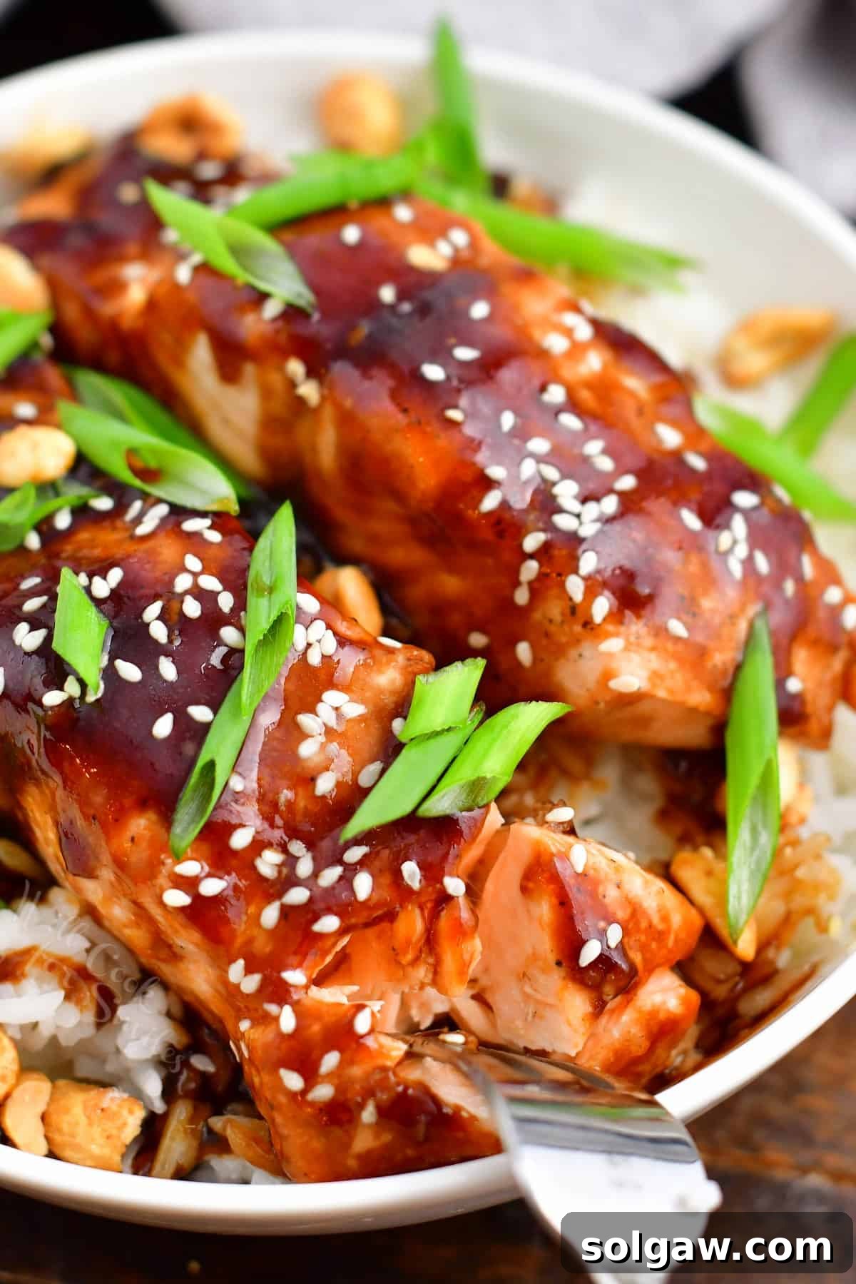 Sticky Sweet Teriyaki Salmon 8 closeup: metal fork flaking teriyaki salmon in a bowl of white rice