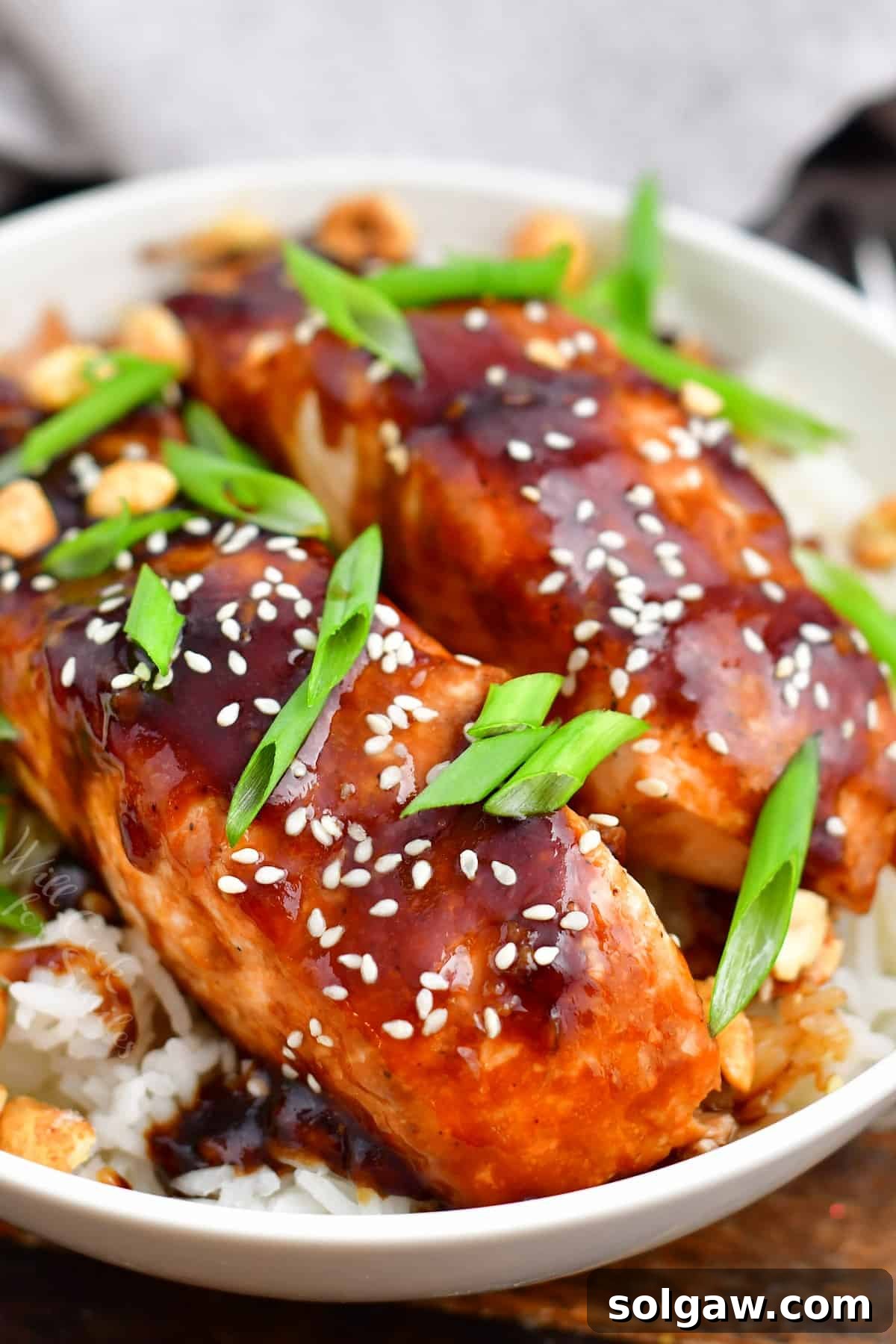 teriyaki baked salmon topped with scallions and sesame seeds on a bed of fluffy rice