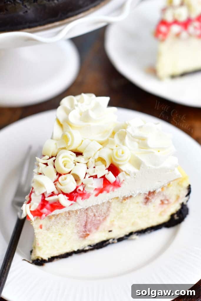 A delectable slice of white chocolate raspberry cheesecake on a pristine white plate, accompanied by a fork, showcasing its layers of chocolate crust, swirled filling, and creamy frosting.