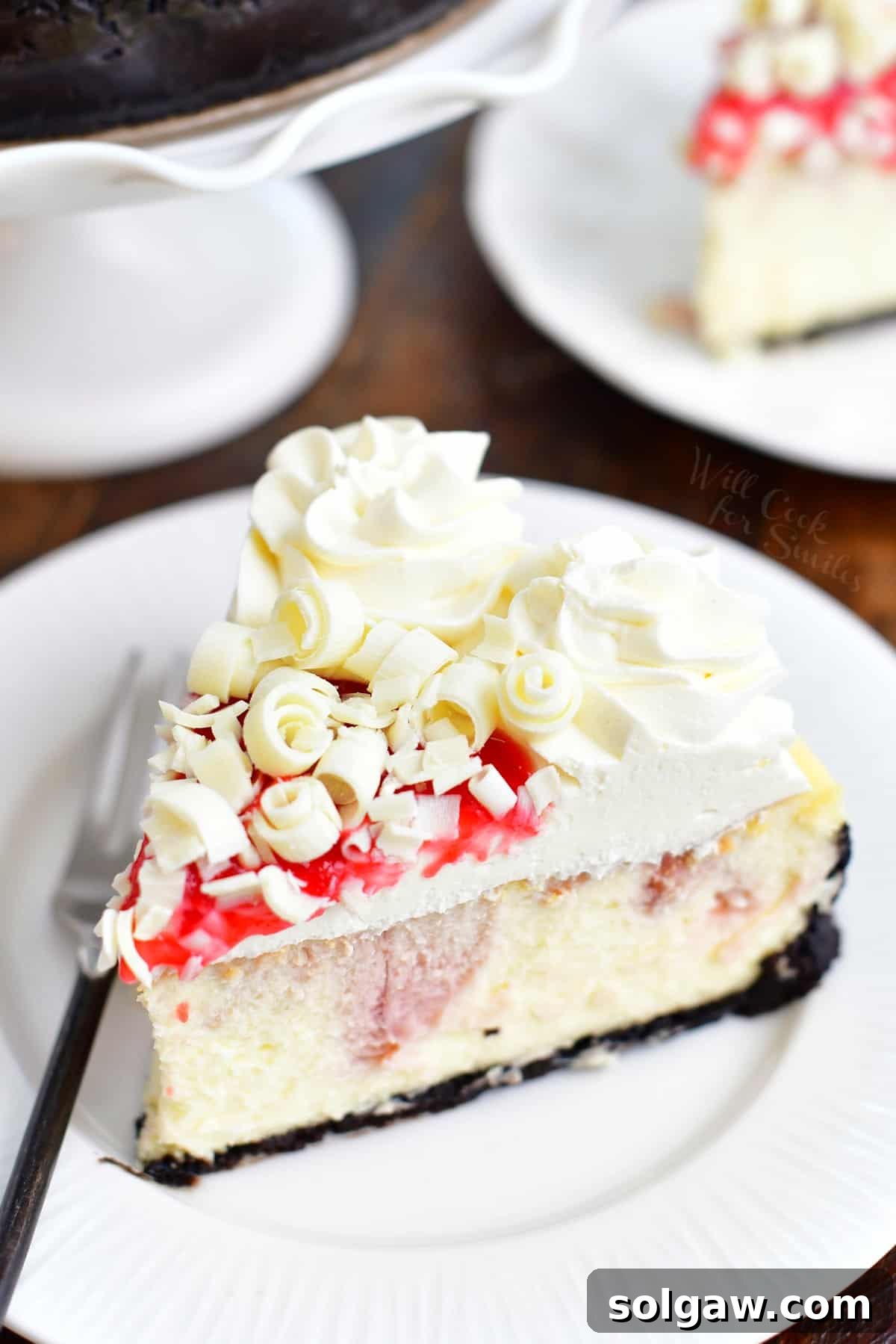 slice of white chocolate raspberry cheesecake on a white plate with a fork