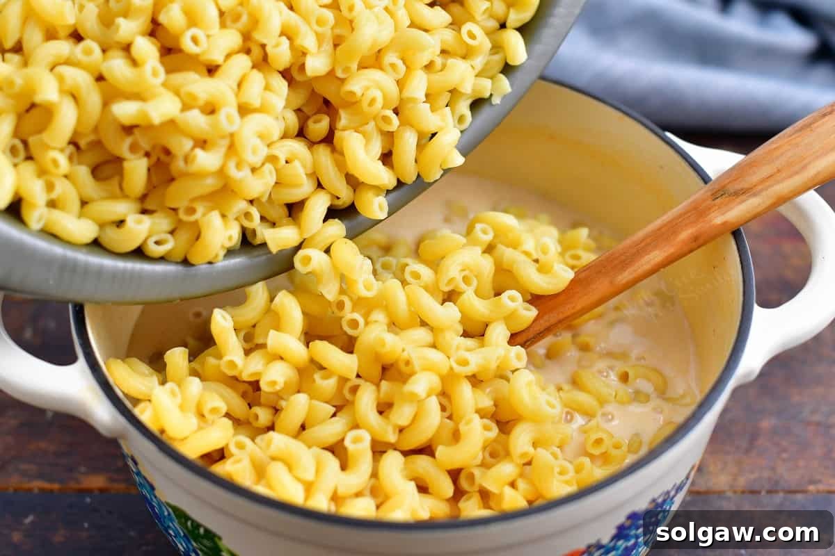 Craft Beer Mac and Cheese 6 cooked pasta being poured into a pot of cheese sauce