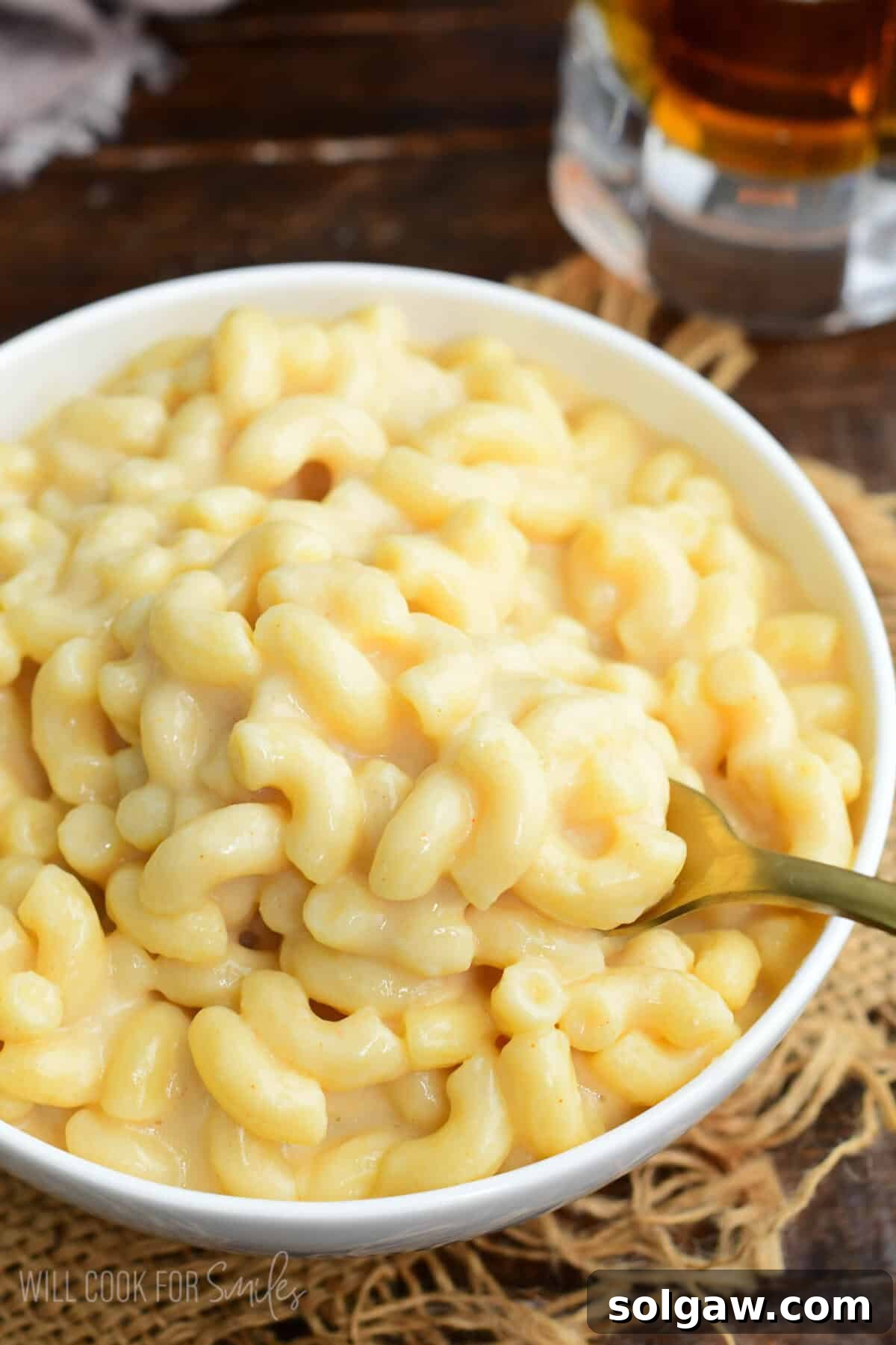 Bowl of creamy beer macaroni and cheese with a spoon scooping cheesy elbow pasta.