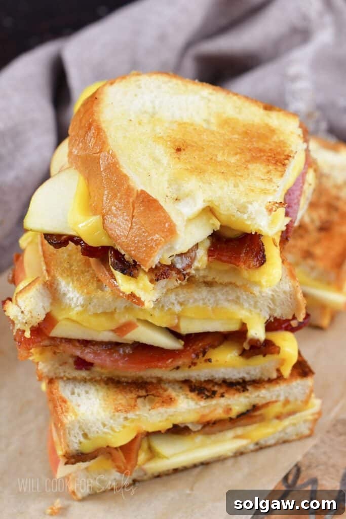 Three stacked grilled cheese halves with one piece bitten, showing the melty interior.