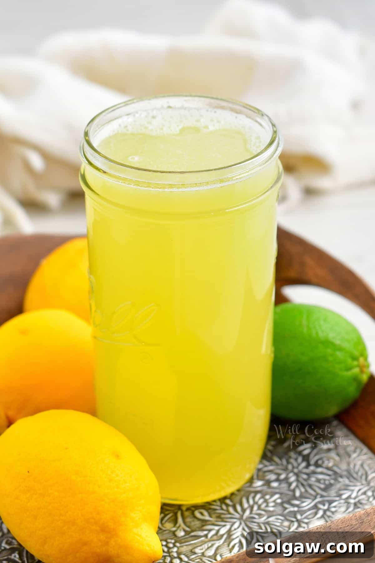 Close-up of a glass jar filled with bright yellow sweet and sour mix, with a texture around the rim indicating freshness and homemade quality. Focuses on the appealing color and clarity of the mix.