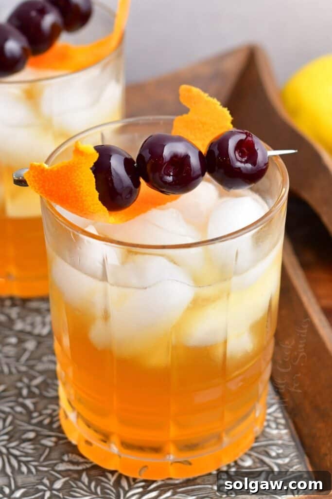 Velvet Almond Sour 2 Three olives on a toothpick and an orange peel garnish an amaretto sour. The cocktail is presented in an elegant glass with a full complement of ice.