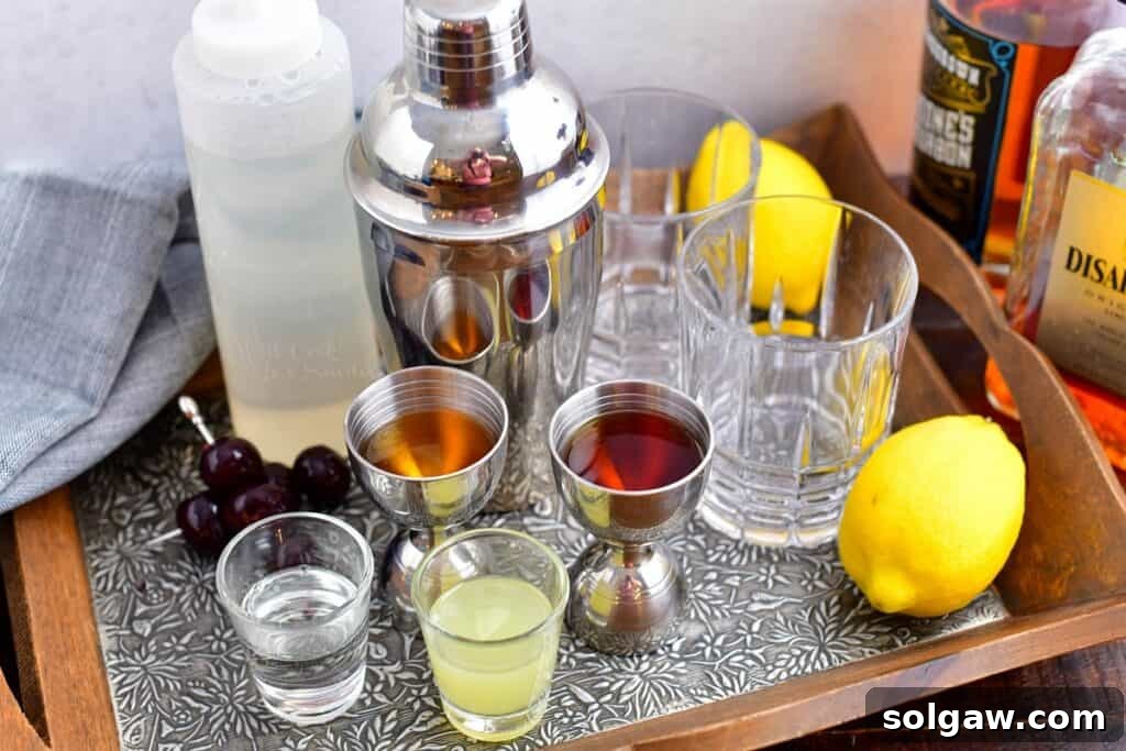 Velvet Almond Sour 3 The ingredients for amaretto sour are spread out on a metal surface, including bottles of amaretto and bourbon, fresh lemons, and simple syrup.