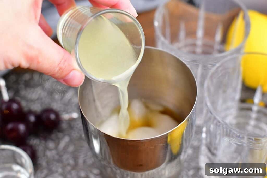 Velvet Almond Sour 6 Lemon juice is being carefully added to the cocktail shaker, joining the other ingredients.