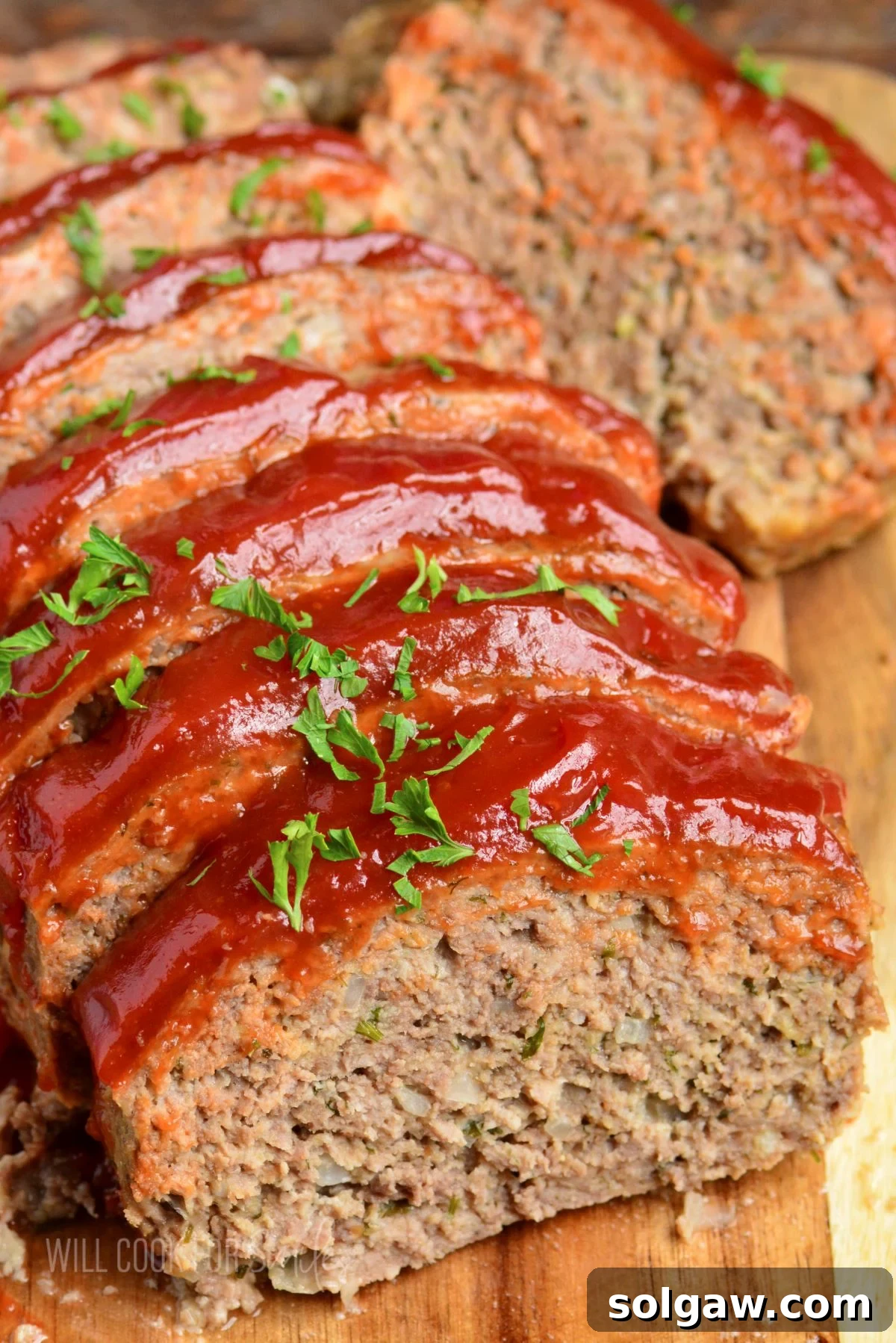 Front view of several slices of homemade meatloaf on a rustic wooden cutting board, ready to be served.